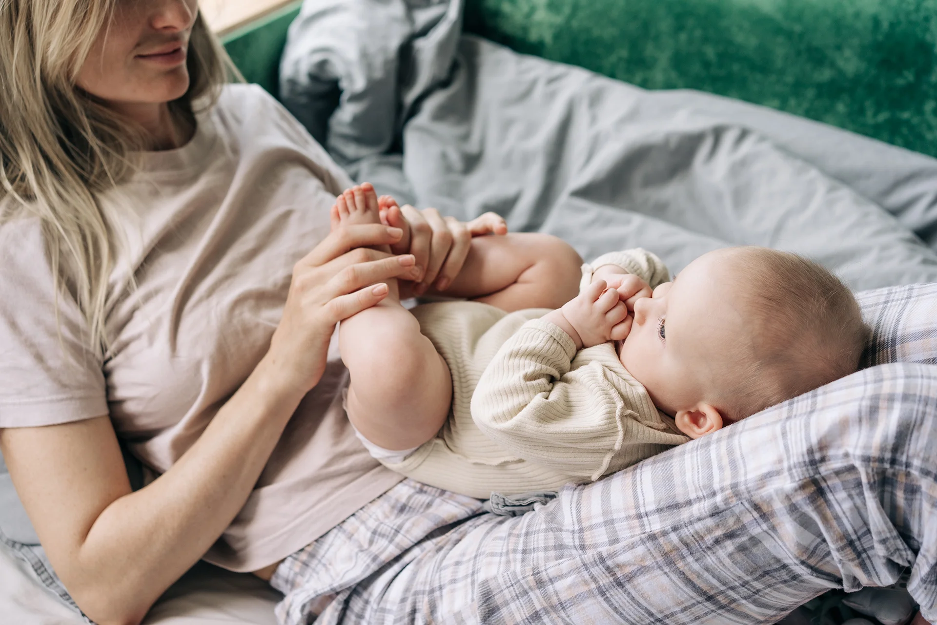 blonde woman cradling a baby indoors