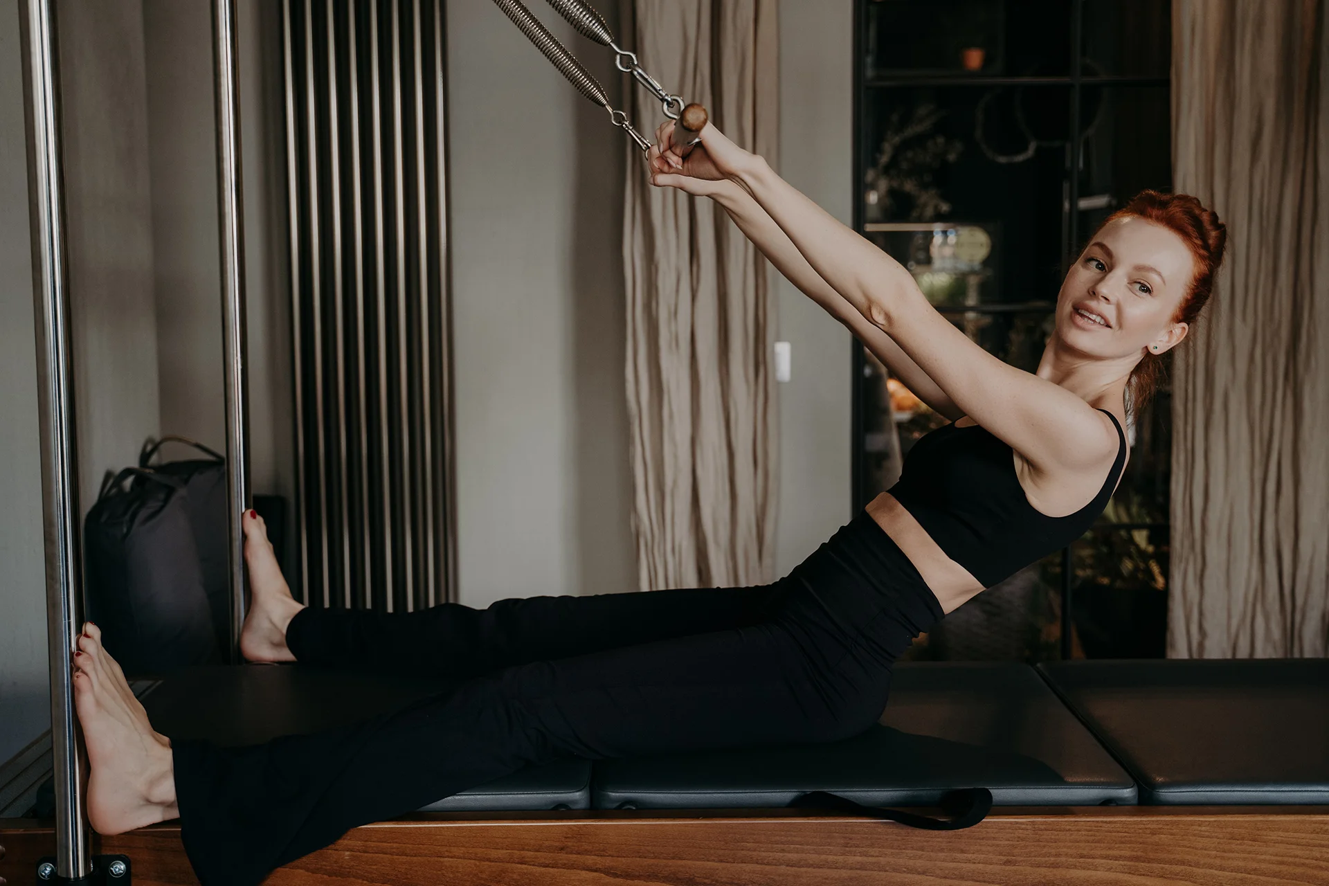 young redhead woman exercising on pilates cadillac