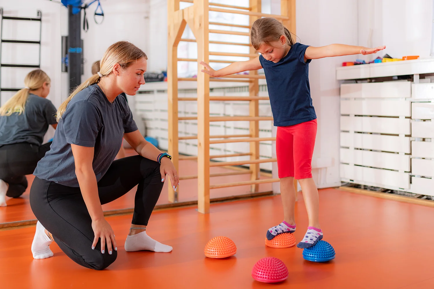 child balancing with assistance in a therapy room