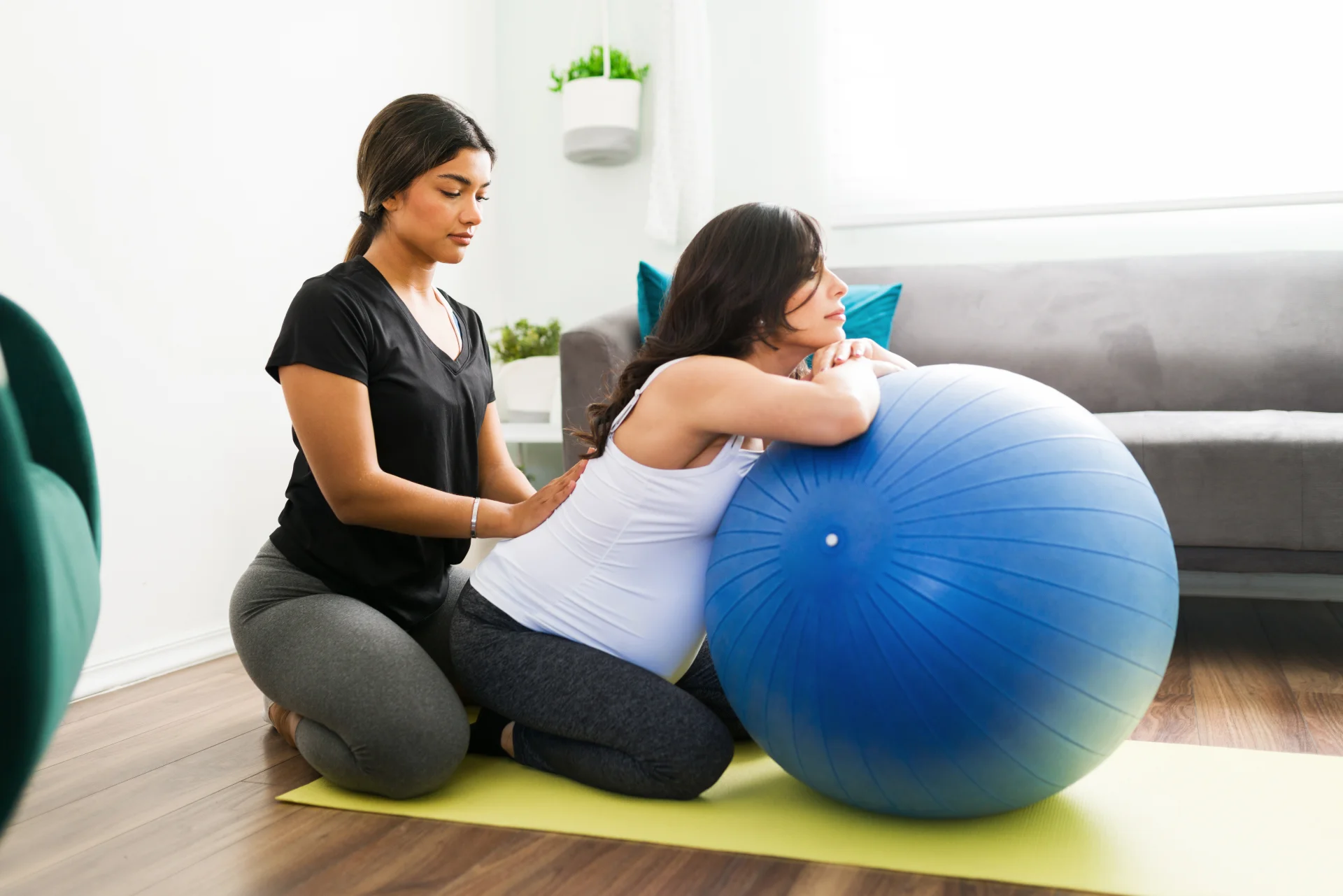 pregnant woman using exercise ball with assistance